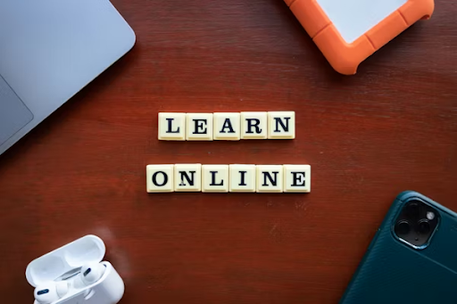 Learn Online text with laptop, smartphone and earbuds on desk representing online education and e-learning